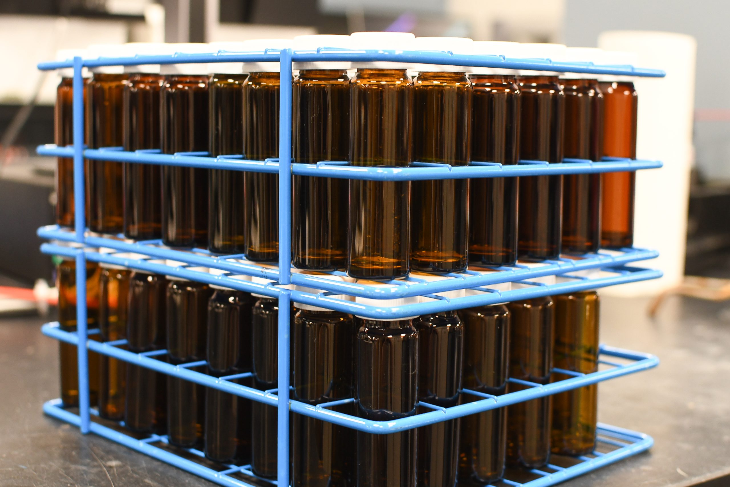 Brown test bottles stored in a blue rack in a lab.